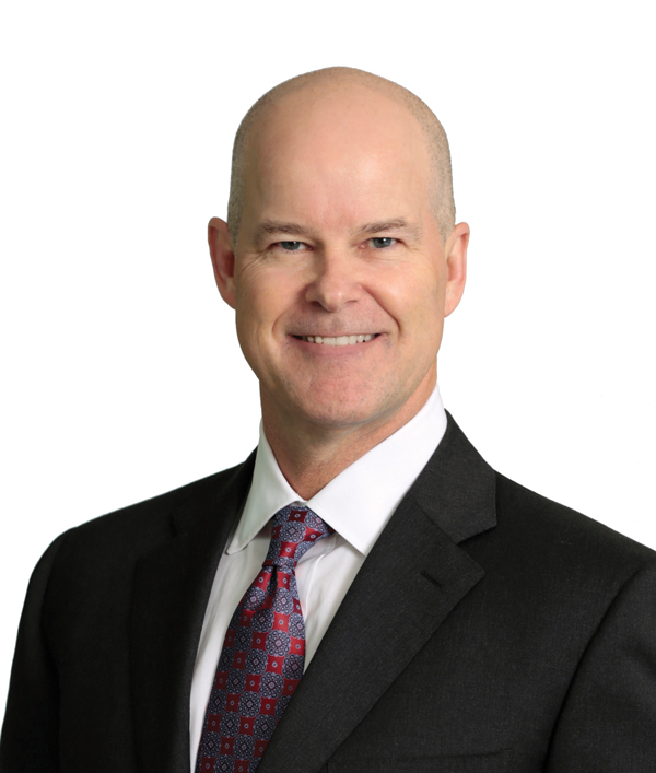 David Breach wearing a dark suit, white shirt and gray and red tie